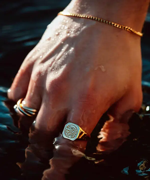 Hånd med Northern Legacy ring og armbånd i vandet